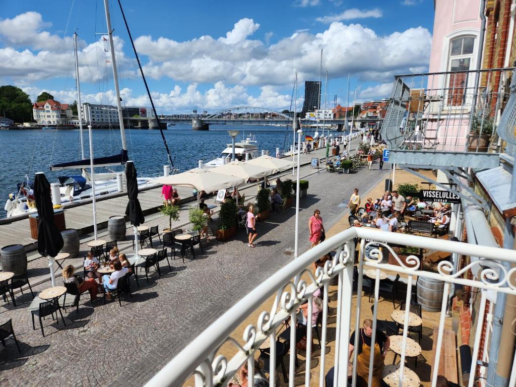 a balcony with people sitting at tables on the water at Harbour View in Sønderborg