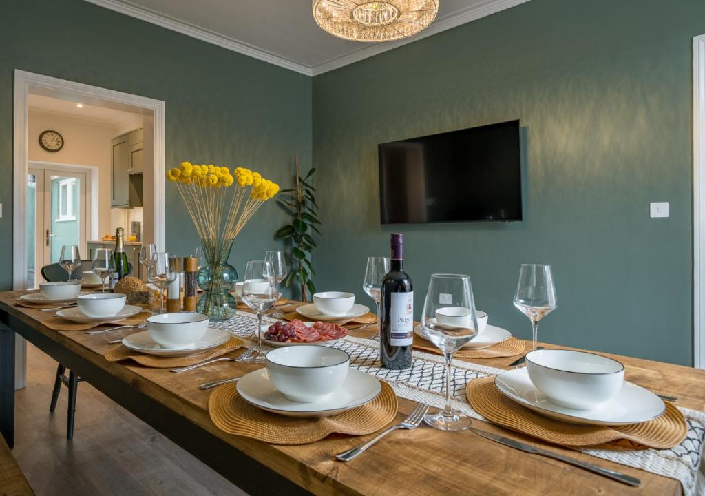 a wooden table with plates and wine glasses on it at Clifton Town House with Cinema Room Perfect for Groups, Families, Friends Hens & Stags! in Bristol