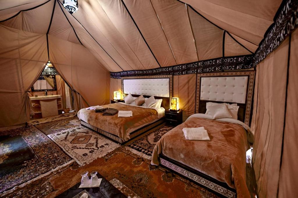 sypialnia z 2 łóżkami w namiocie w obiekcie Ahlam Luxury Camp w mieście Merzouga