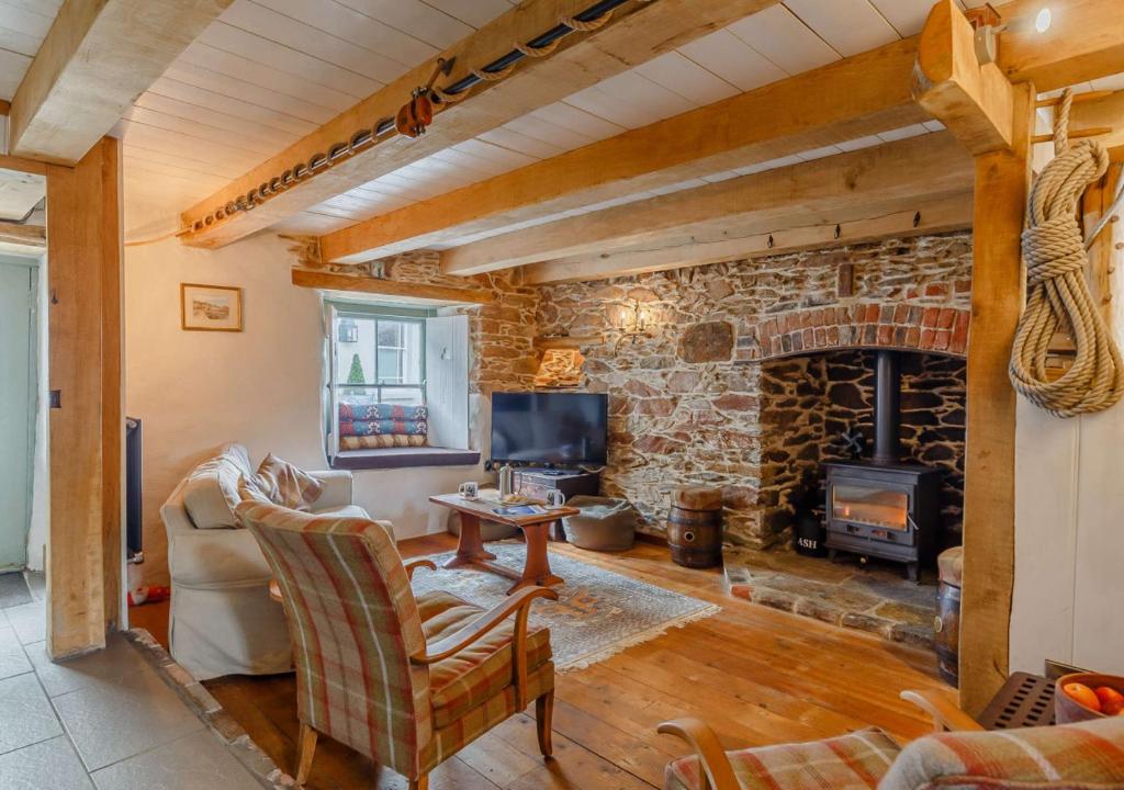 a living room with a stone fireplace and a tv at Alpha Cottage in Dittisham