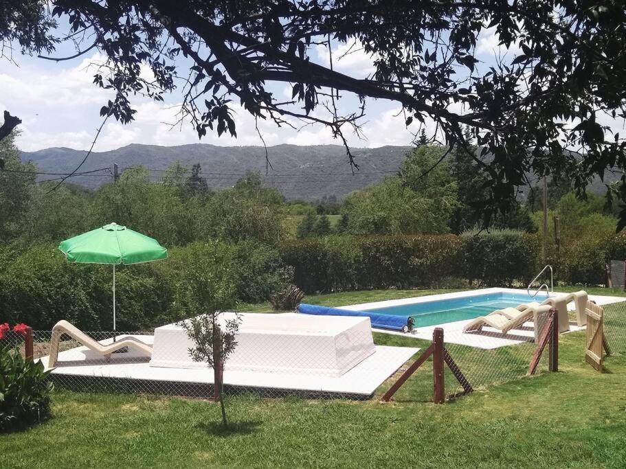 a swimming pool with a slide and an umbrella at Cabaña para relajarse con vista panorámica in Villa General Belgrano
