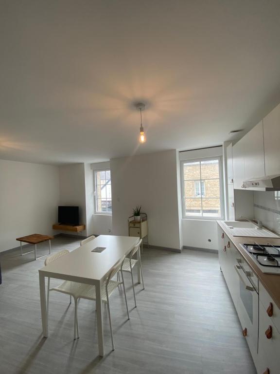 une cuisine blanche avec une table et des chaises dans l'établissement Résidence de la poste, à Saint-Pol-de-Léon