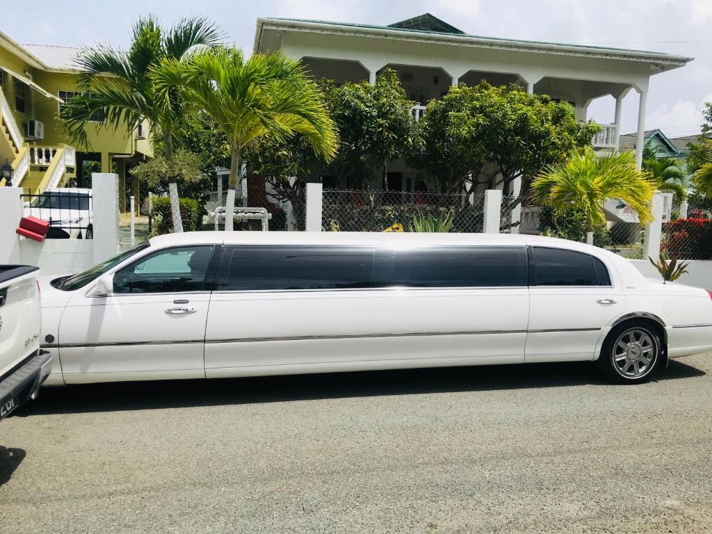 a white limo parked in front of a house at HCeas Villa Compound is 5 minutes from the airport and beaches, can sleep up to 30 ppl in Bon Accord