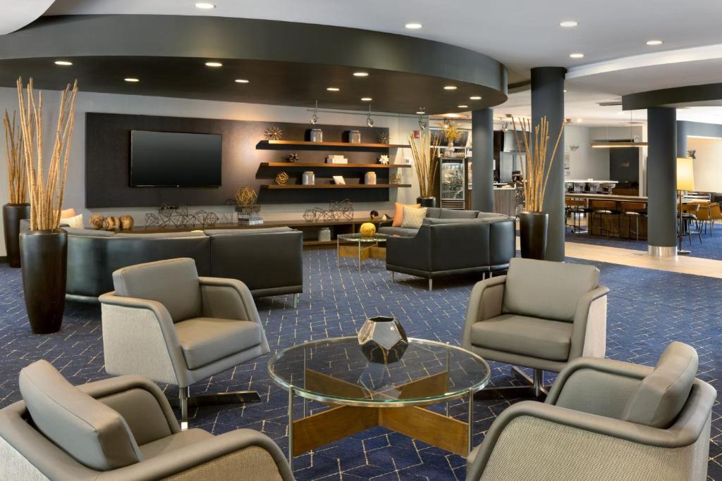 a lobby with a waiting room with chairs and a tv at Courtyard Edison Woodbridge in Edison