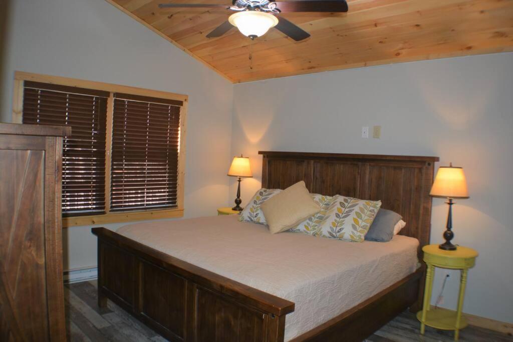 a bedroom with a bed with a ceiling fan and two lamps at Cozy cabin with boosted Wi-Fi in Beech Mountain