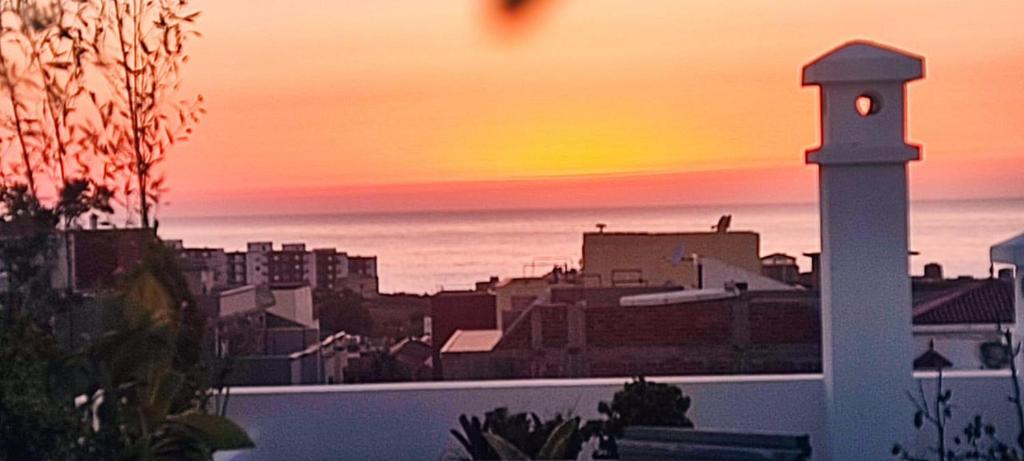 a view of a city at sunset with a lighthouse at luxe appartement Nour D'asilah 3 in Asilah