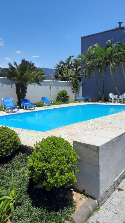 una grande piscina con sedie e un edificio di Lindo Sobrado com Piscina em Condomínio Fechado a Bertioga