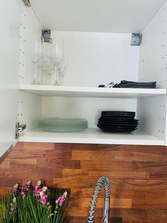 a kitchen shelf with plates and glasses on it at jolie maison individuelle 50 m2 ,design et climatisée, tout confort, wifi, terasse privée , 5 min plage et autoroute, stationnement gratuit in Marseille