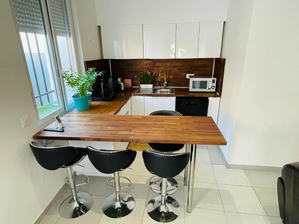 a kitchen with a wooden table and four bar stools at jolie maison individuelle 50 m2 ,design et climatisée, tout confort, wifi, terasse privée , 5 min plage et autoroute, stationnement gratuit in Marseille