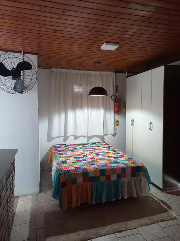 a bedroom with a bed with a colorful quilt on it at Pousada do centro Vino & Leta in Grão Pará