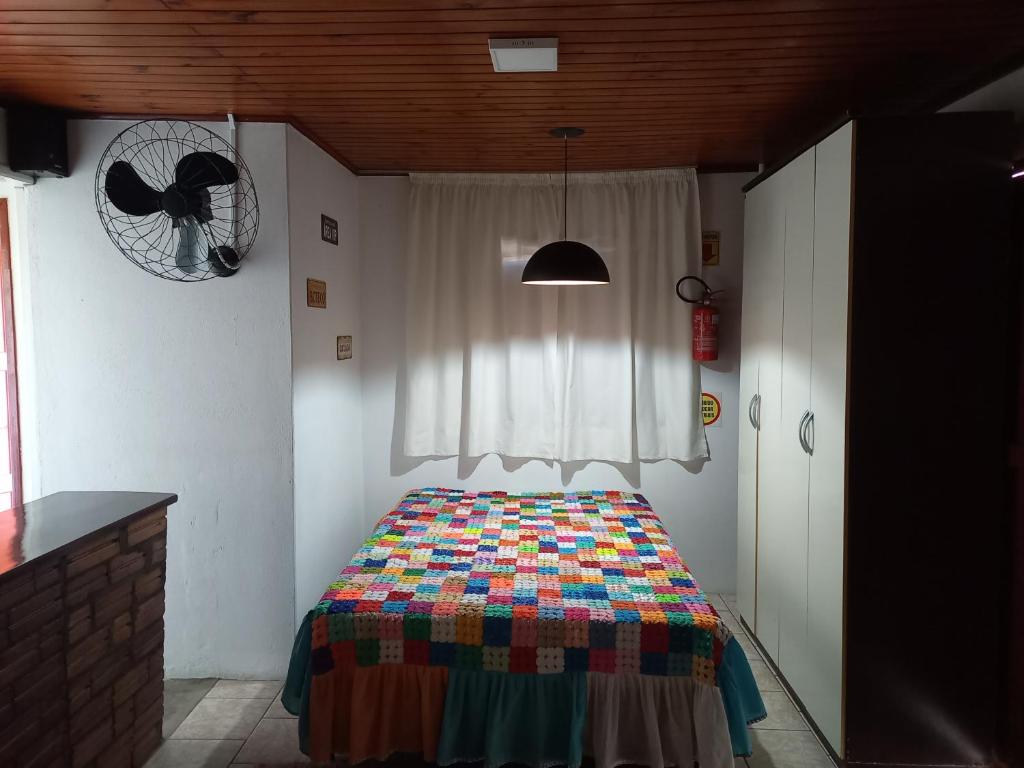 a bedroom with a bed with a colorful blanket at Pousada Vino & Leta O seu parador no centro in Grão Pará