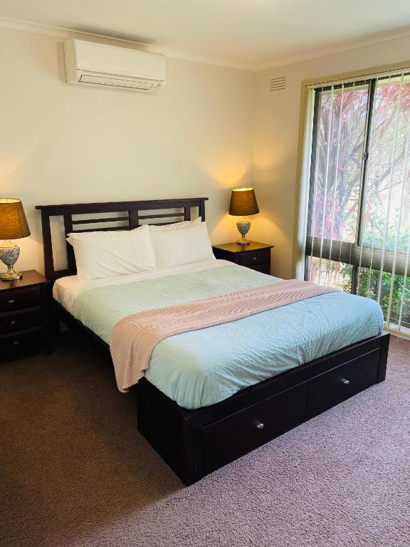 a bedroom with a large bed with two lamps and a window at Intrigue FREE WI-FI in Apollo Bay
