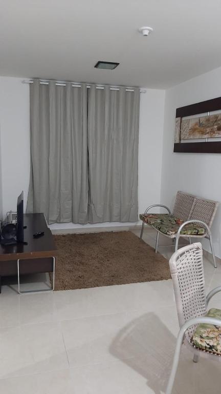 ein Wohnzimmer mit einem Tisch, Stühlen und einem Fenster in der Unterkunft Jockey Family_Villaggio di Piazza in Vila Velha