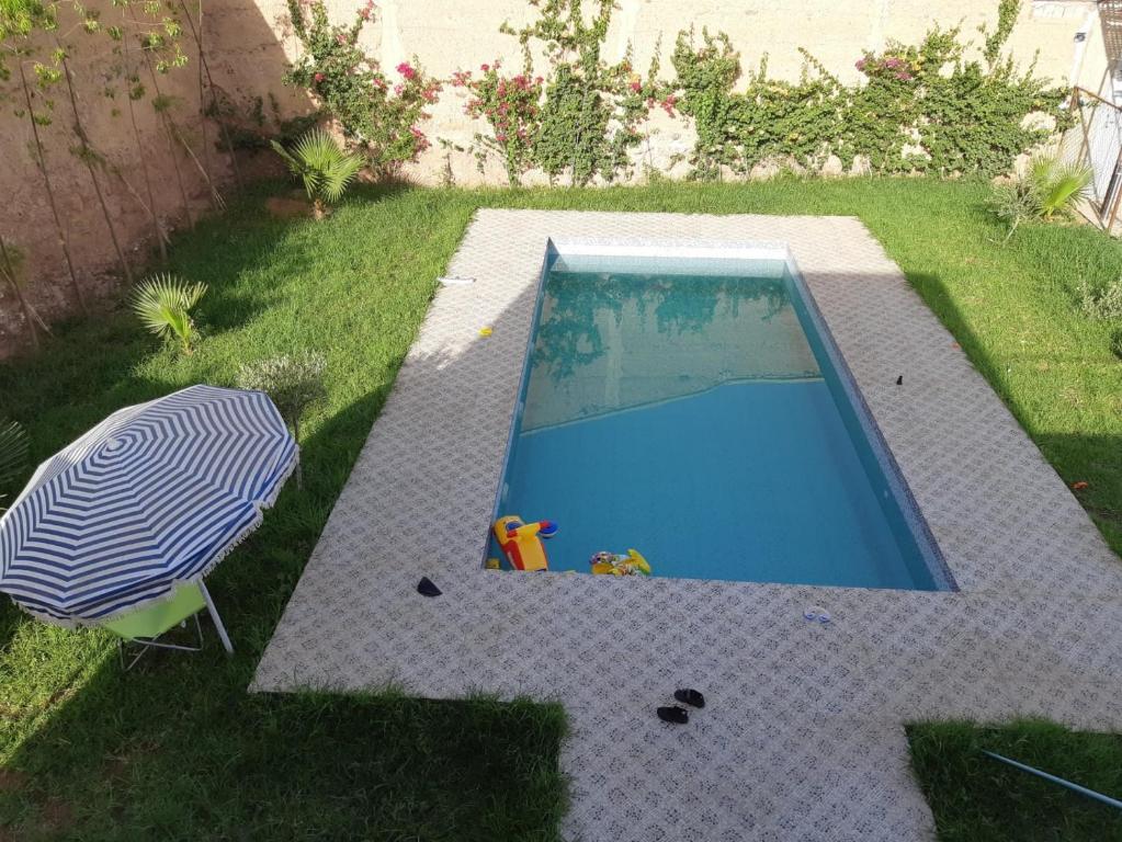 ein kleiner Pool mit Sonnenschirm und Stuhl in der Unterkunft BUILD KECH Agafay Marrakech in Marrakesch