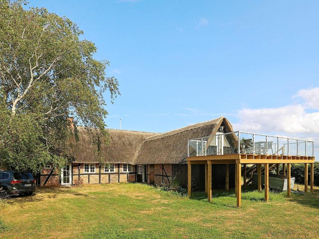 a house with a thatched roof with a deck at Holiday home Guldborg II in Guldborg