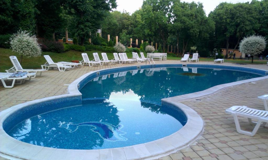 een zwembad met witte stoelen en stoelen in een tuin bij Luxury Sunrise Complex Apartment in Goudstrand