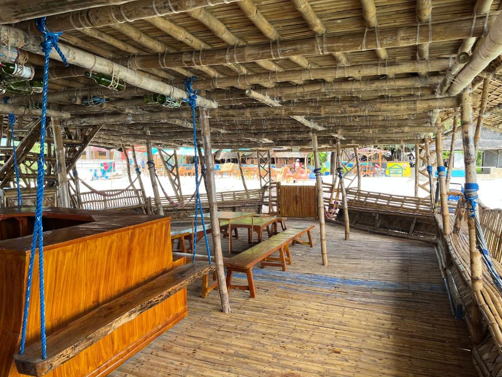 a wooden porch with benches and a beach at Bamboo Nest Beachfront Floating Tent in Puerto Princesa City