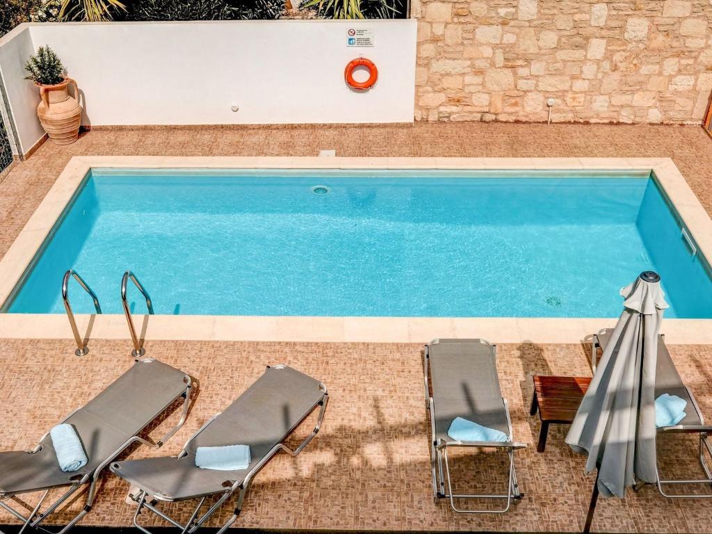 a swimming pool with two chairs and a table at Luxury Villa in Kalamitsi Alexandrou in Kalamítsion Alexándrou