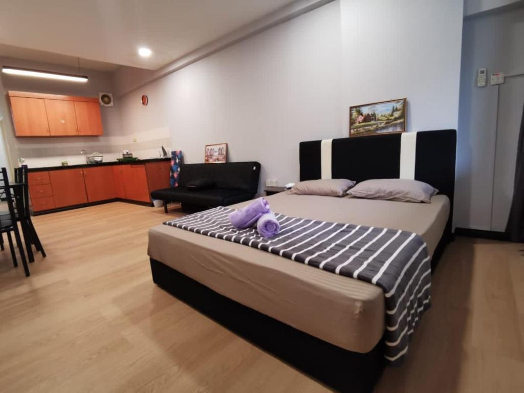 a bedroom with a large bed and a kitchen at KK City Api Api Apartment beside Centre Point by JR Homestay in Kota Kinabalu