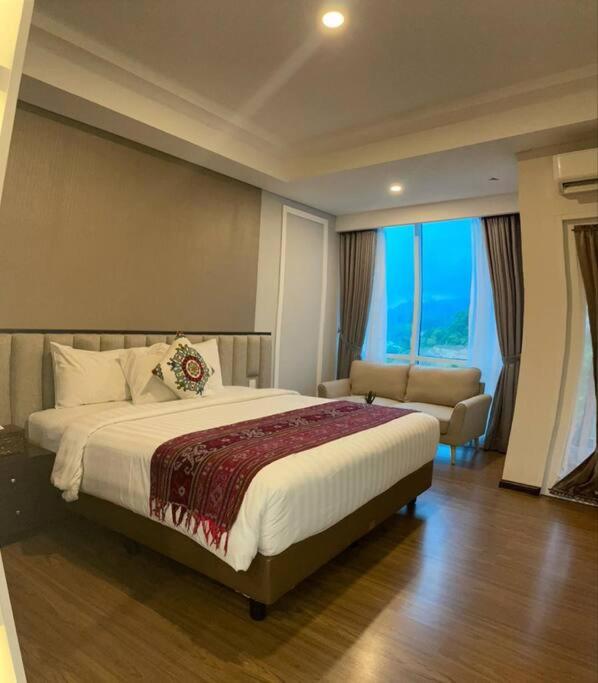 a bedroom with a bed and a couch and a window at Apartment Panbil with Gym & Pool #Unit 603 in Nagoya