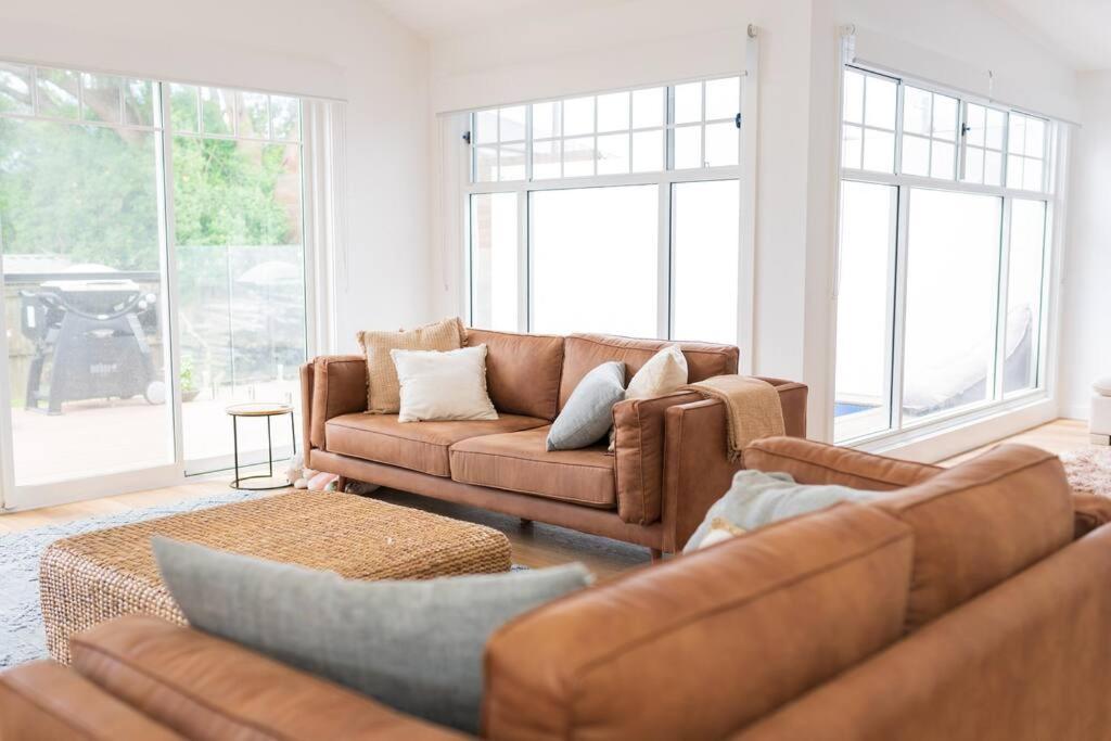 uma sala de estar com sofás e janelas castanhos em Kiama Family Beach House em Kiama Downs