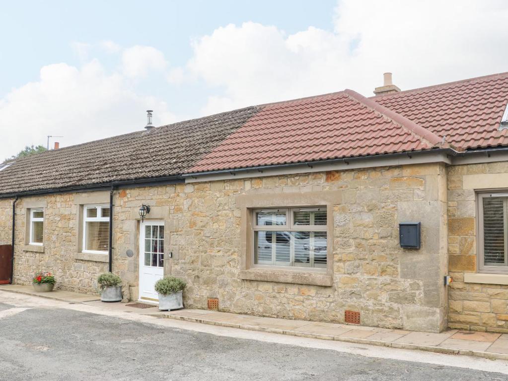 an old stone house with a red roof at Stable Cottage in Belford