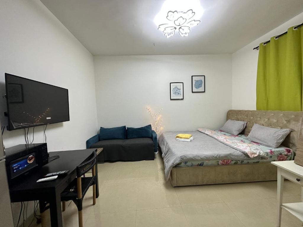 een woonkamer met een bank, een bureau en een televisie bij Khalidiya Studio Villa 6 Room 13 Abu Dhabi UAE in Abu Dhabi