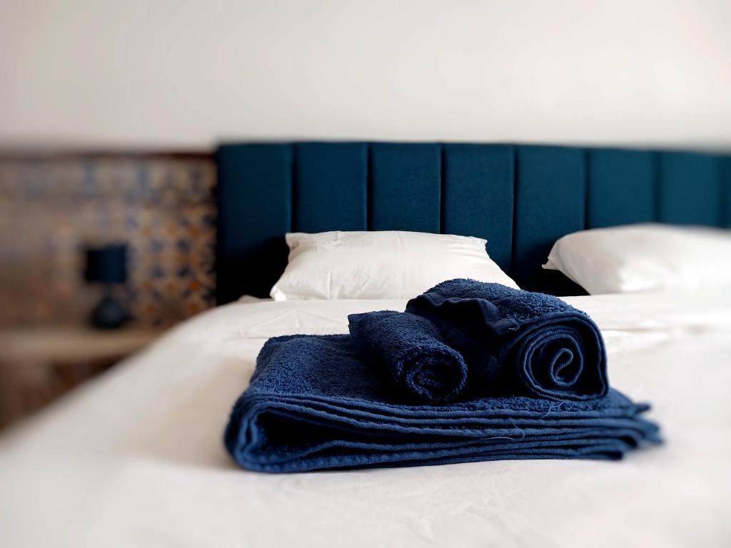 a pile of towels sitting on top of a bed at Rooms 10 mins walk from train station! in Agualva