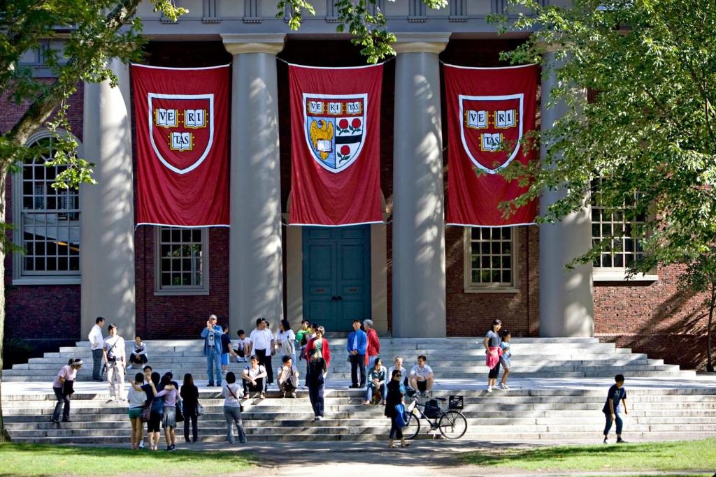 een groep mensen die op de trappen van een gebouw met vlaggen lopen bij 4 Bedroom Condo At Harvard Square and Harvard University in Cambridge