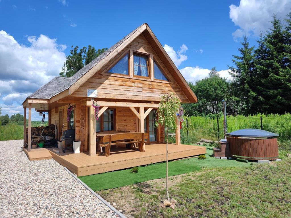 ein kleines Haus mit einer großen Terrasse und einer Badewanne in der Unterkunft Domek z bala na Podlasiu z balią ogrodową 