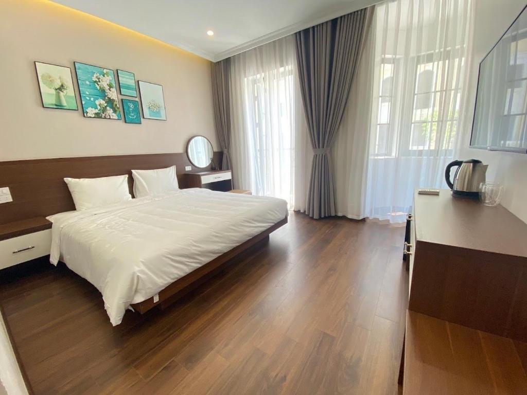 sypialnia z dużym białym łóżkiem i drewnianą podłogą w obiekcie MOONLIGHT HOTEL w Ha Long