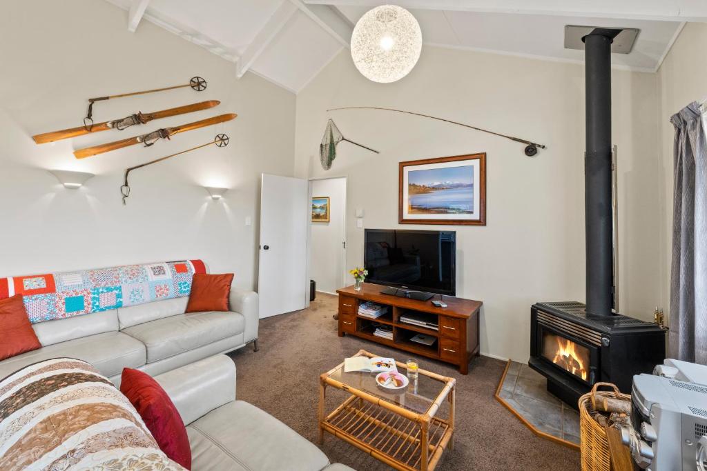 een woonkamer met een bank en een houtkachel bij Greenhaven with wi-fi in Taupo