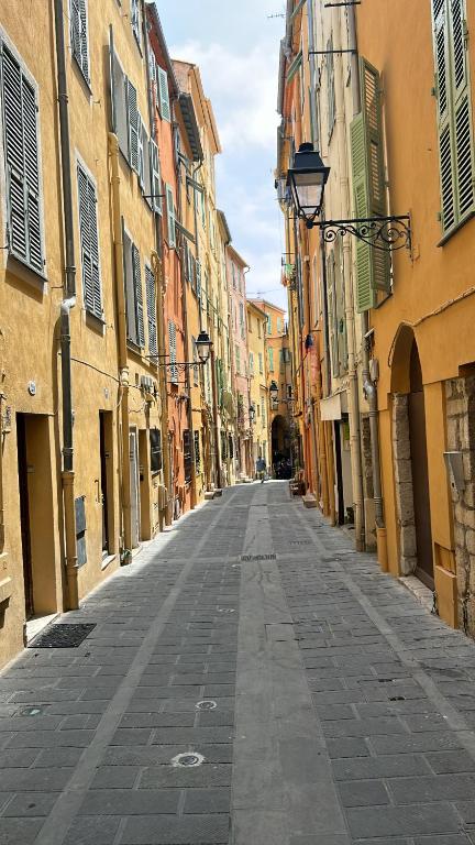 une rue vide dans une ruelle entre bâtiments dans l'établissement MAGNIFIQUE 3p VUE MER À 5 MIN DE LA PLAGE, à Menton