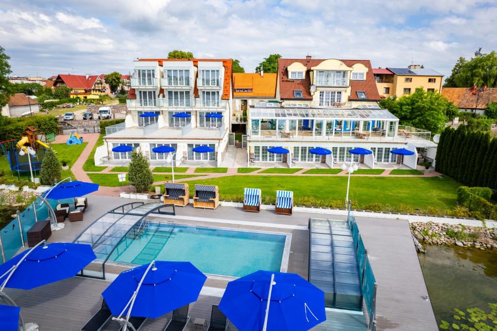 a hotel with a swimming pool and blue umbrellas at Villa Le Lux in Mikołajki