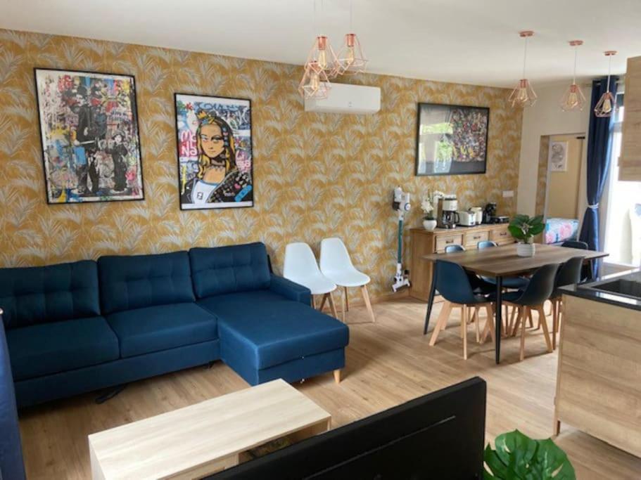 ein Wohnzimmer mit einem blauen Sofa und einem Tisch in der Unterkunft La Maison Passageon, Tout confort in Châteauroux