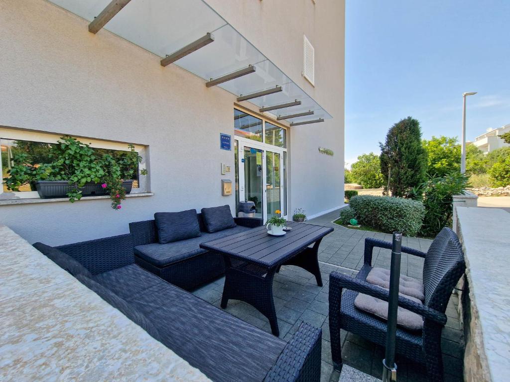 a patio with a couch and a table and chairs at Vila Novak in Novalja