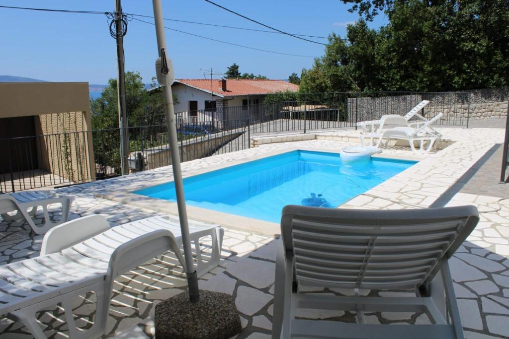 einen Pool mit Stühlen und einem Sonnenschirm daneben in der Unterkunft Apartment INES 2 with terrace, sea view, Jacuzzi, outdoor pool in Novi Vinodolski