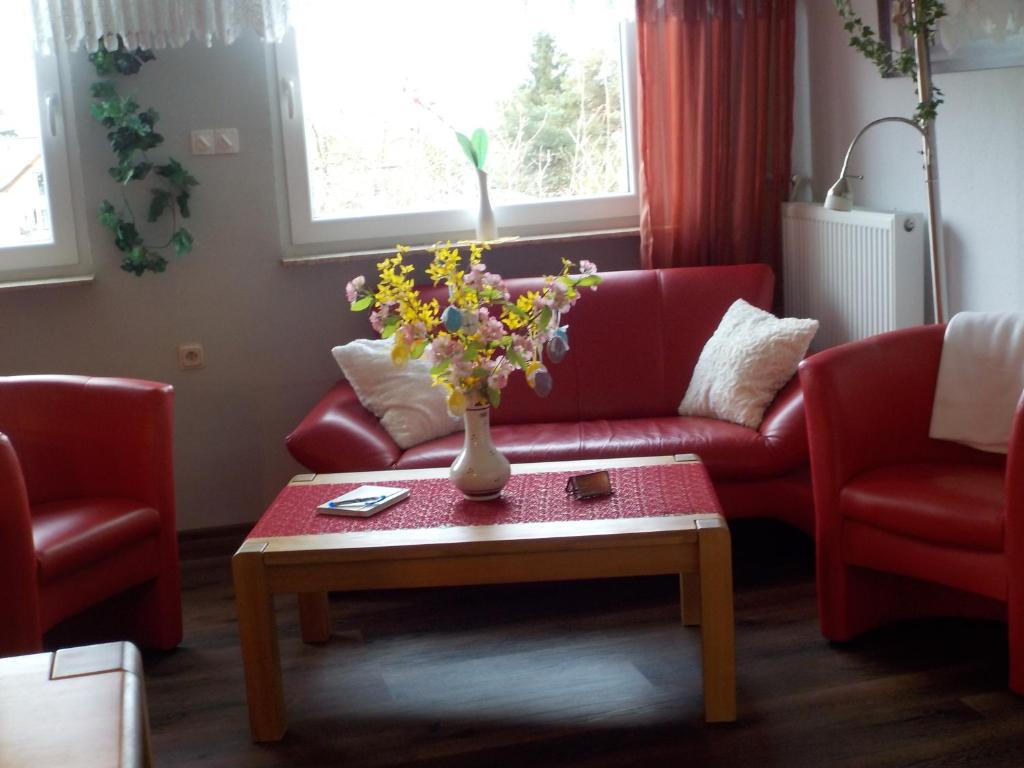a living room with a red couch and a table with flowers at Ferienwohnung Wolf in Ensdorf