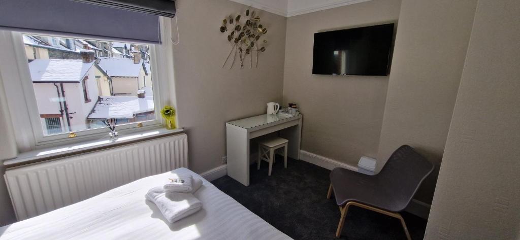 ein Hotelzimmer mit einem Bett, einem Stuhl und einem Fenster in der Unterkunft Glencoe Guest House in Keswick