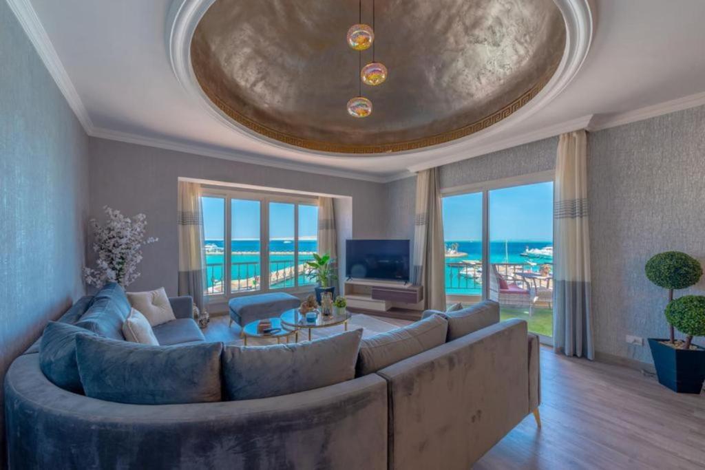 Hurghada marina apartment sea view في الغردقة: غرفة معيشة كبيرة مع أريكة كبيرة ونافذة كبيرة