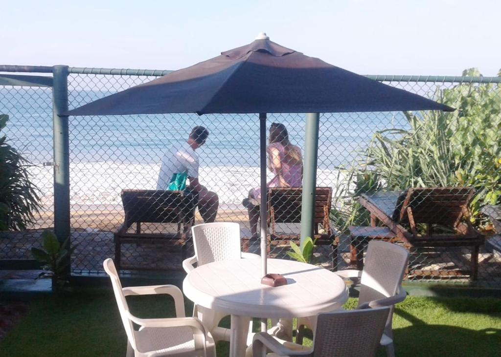 two people sitting under an umbrella on a table at Beach Villa Randiya in Galle