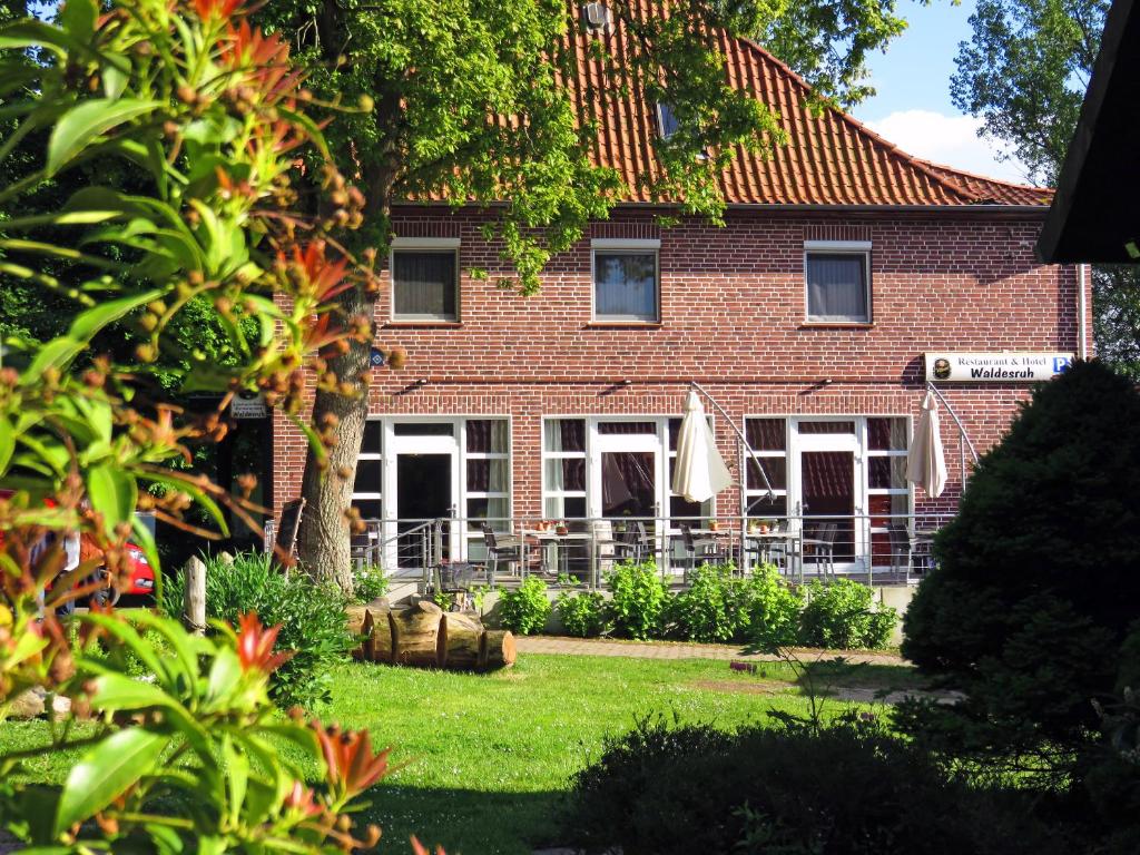 ein rotes Backsteinhaus mit einem grünen Hof in der Unterkunft Land-gut-Hotel Waldesruh in Altenmedingen