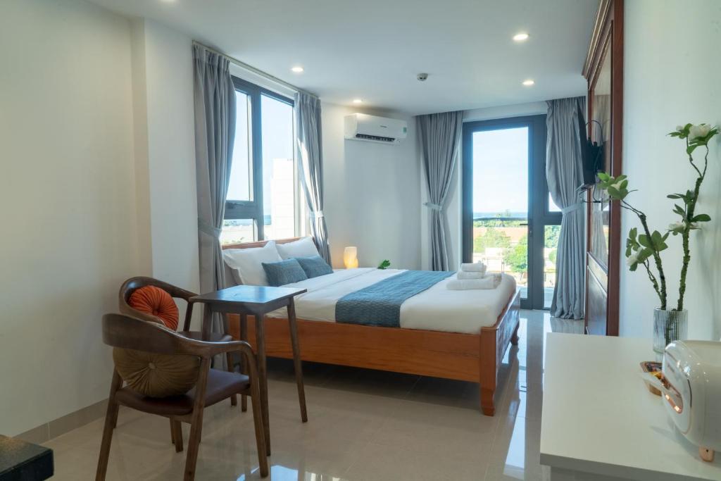 um quarto com uma cama e uma mesa e algumas janelas em Ha Trang Voronezh Hotel and Apartment em Nha Trang