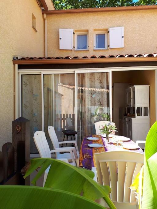 d'un patio avec des chaises blanches et une table. dans l'établissement Pavillon Duplex T2/terrasse, au Cap d'Agde