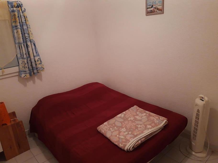 een rood bed in een hoek van een kamer bij Pavillon Duplex T2/terrasse in Cap d'Agde