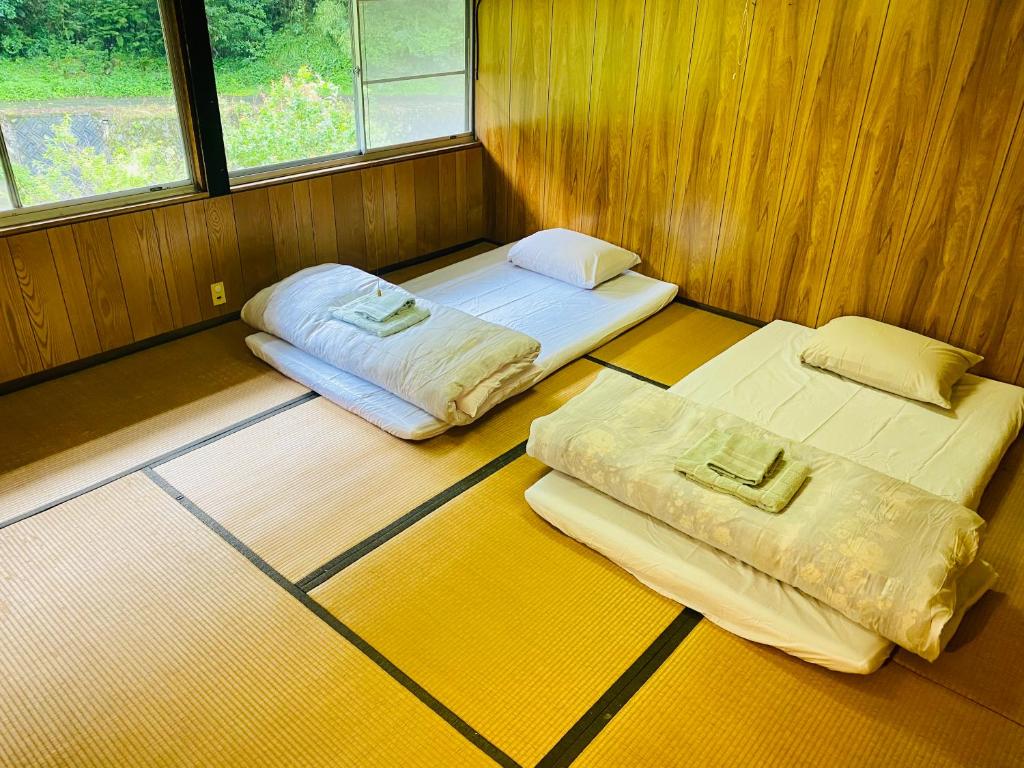 two beds in a room with two windows at Yubara Hot Springs - Entire Home, Relaxing River Access, Families Welcome in Maniwa