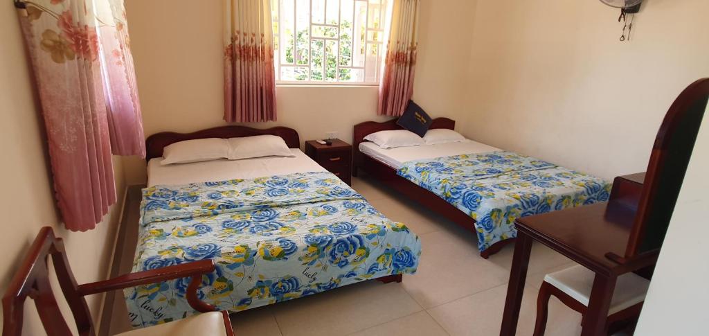 1 Schlafzimmer mit 2 Betten, einem Tisch und einem Fenster in der Unterkunft Khách Sạn Minh Hồng in Long Hải
