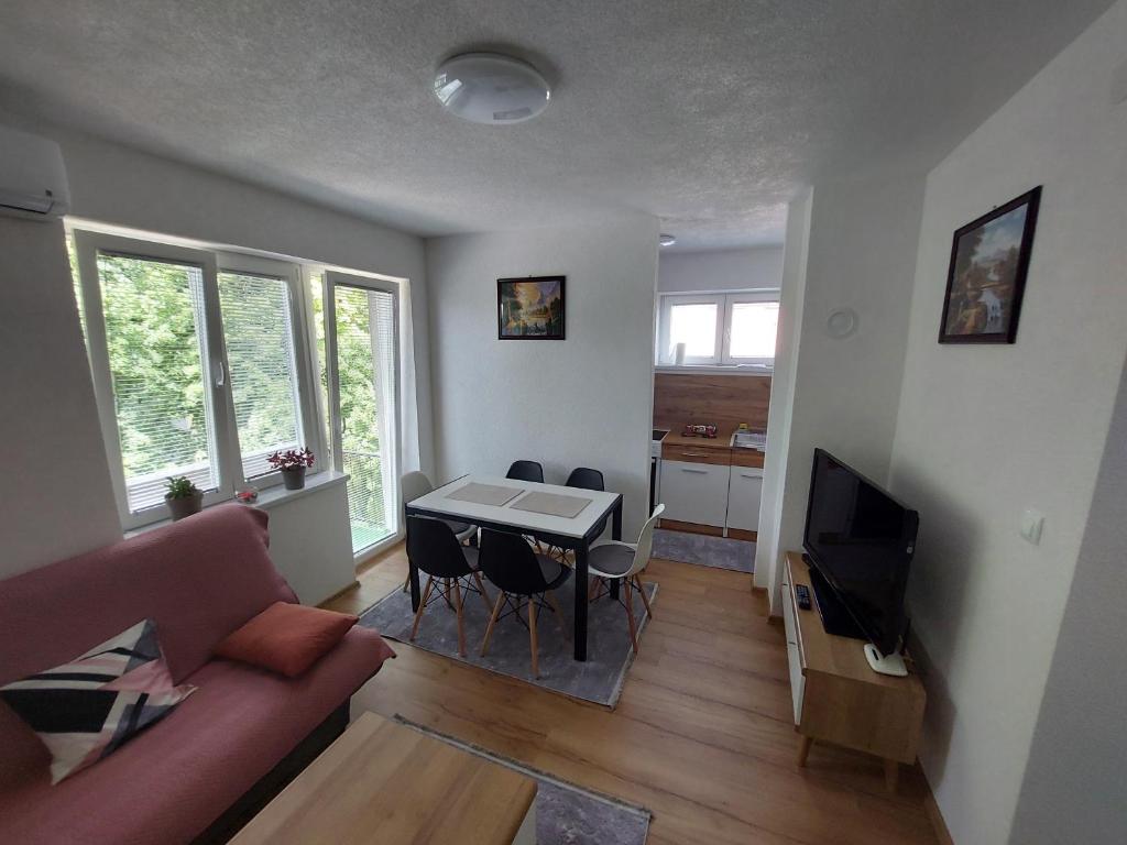 uma sala de estar com um sofá e uma mesa com cadeiras em Apartman "MEDENI" em Bihać