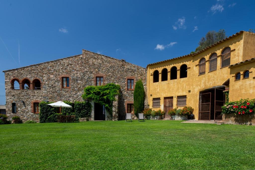 un gran edificio de piedra con un patio verde en Mas Valentí 1511, en Vall-Llobrega