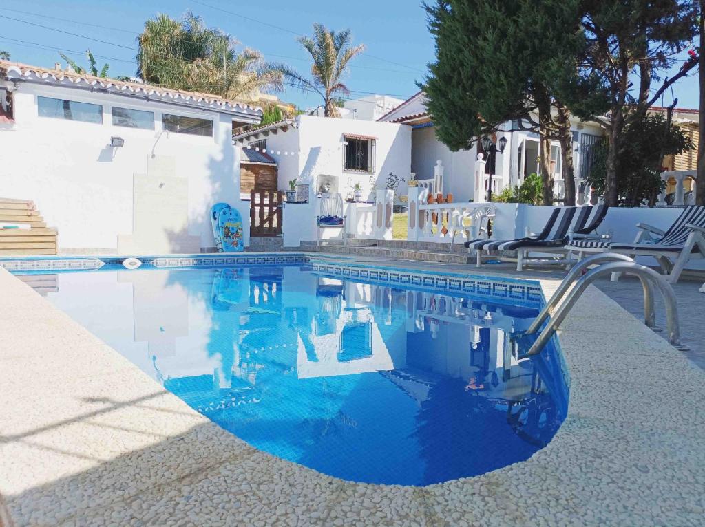 una piscina de agua azul y edificios blancos en Chalet privado buenas noches, en Estepona